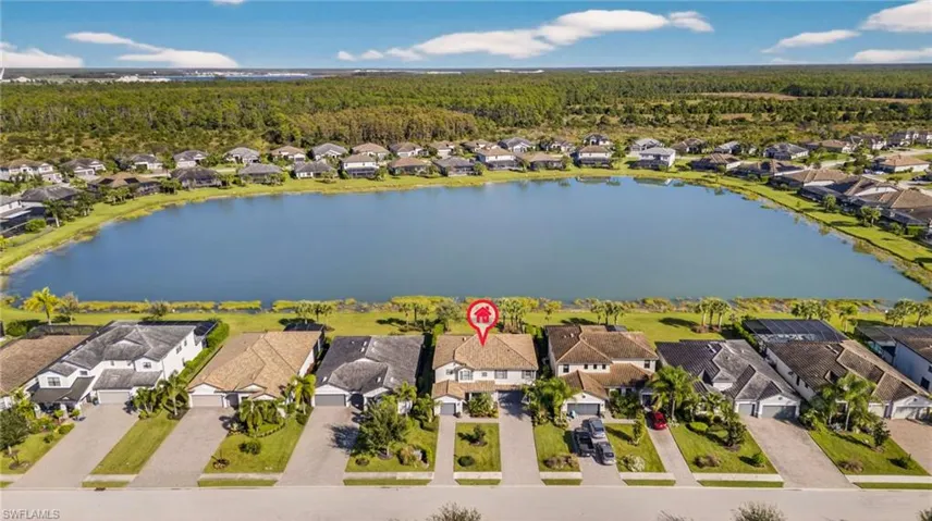 Aerial perspective of suburban area with a nearby body of water and a forest