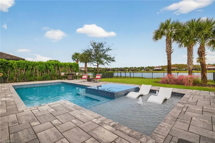 View of swimming pool featuring a fenced backyard, a patio, a pool with connected hot tub, and a water view
