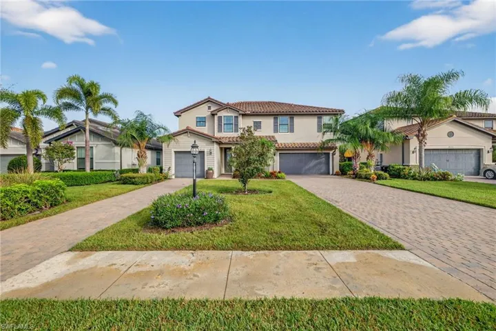 Mediterranean / spanish house with decorative driveway, a front yard, a tiled roof, and stucco siding