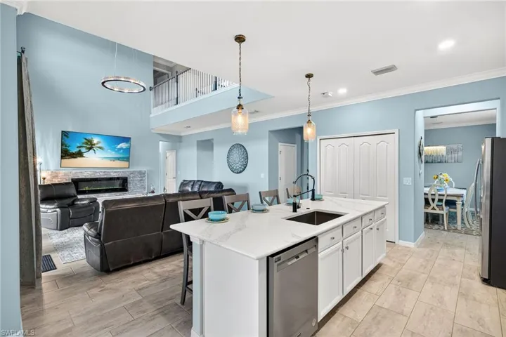 Kitchen featuring a kitchen breakfast bar, appliances with stainless steel finishes, crown molding, a kitchen island with sink, and pendant lighting