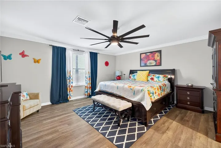 Bedroom featuring light wood-style floors, ornamental molding, and a ceiling fan