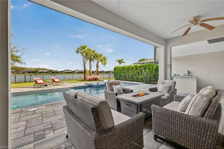 Fenced backyard featuring a patio, ceiling fan, and an outdoor living space with a fire pit