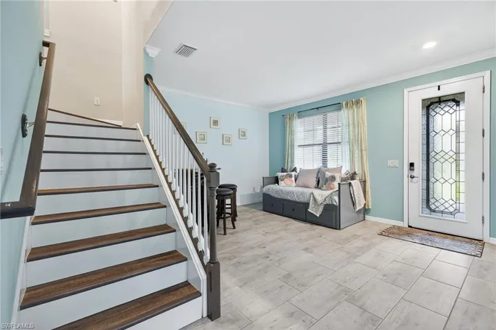 Foyer featuring ornamental molding and stairs