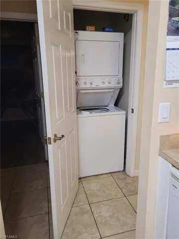 Laundry room with estacked washer and dryer and light tile patterned floors