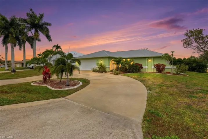 View of front of property featuring curved driveway, a yard, an attached garage, and stucco siding