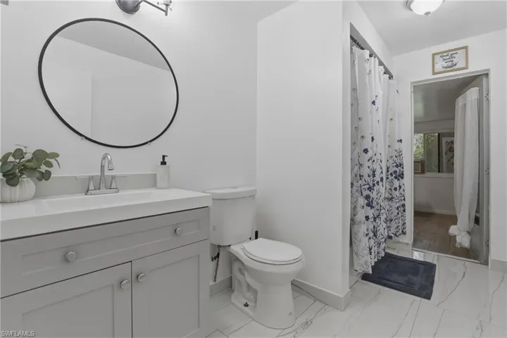 Bathroom featuring vanity, curtained shower, and light marble finish floors