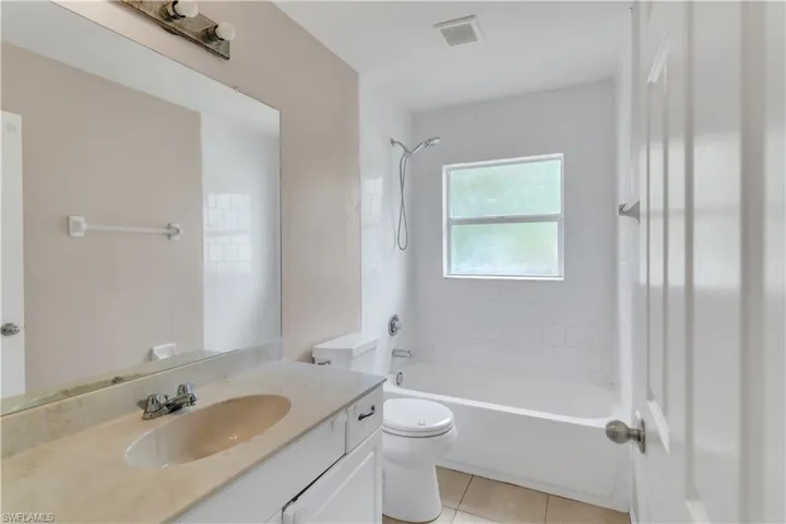 Full bathroom featuring tile patterned flooring, vanity, toilet, and tiled shower / bath combo