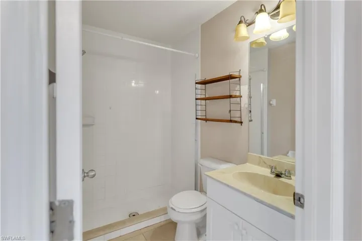 Bathroom featuring tiled shower, tile patterned flooring, vanity, and toilet