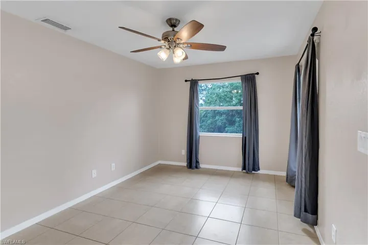 Tiled spare room featuring ceiling fan
