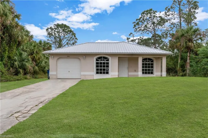 View of front of property with a front yard and a garage