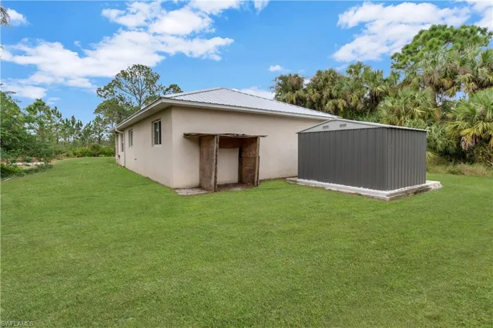 Rear view of house with a lawn and an outdoor structure