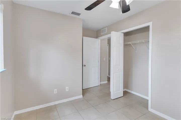 Unfurnished bedroom featuring a closet, ceiling fan, and light tile patterned flooring