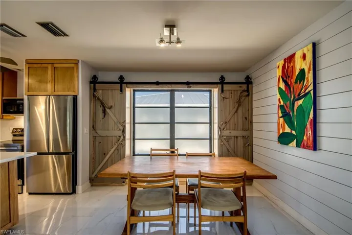 Dining area with a barn door, wood walls, and light marble finish flooring