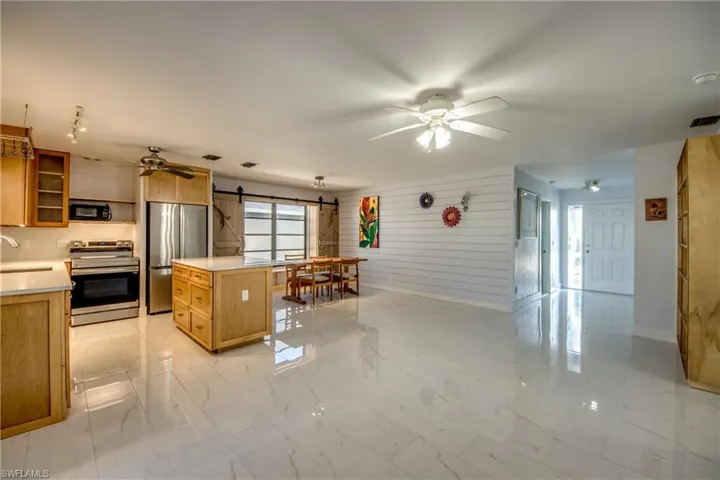 Kitchen featuring a barn door, appliances with stainless steel finishes, light countertops, glass insert cabinets, and ceiling fan