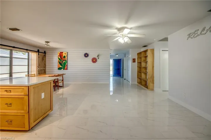 Kitchen featuring light marble finish flooring, light countertops, a barn door, a ceiling fan, and open floor plan