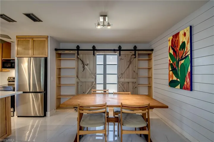 Dining area featuring light marble finish flooring, a barn door, and wood walls