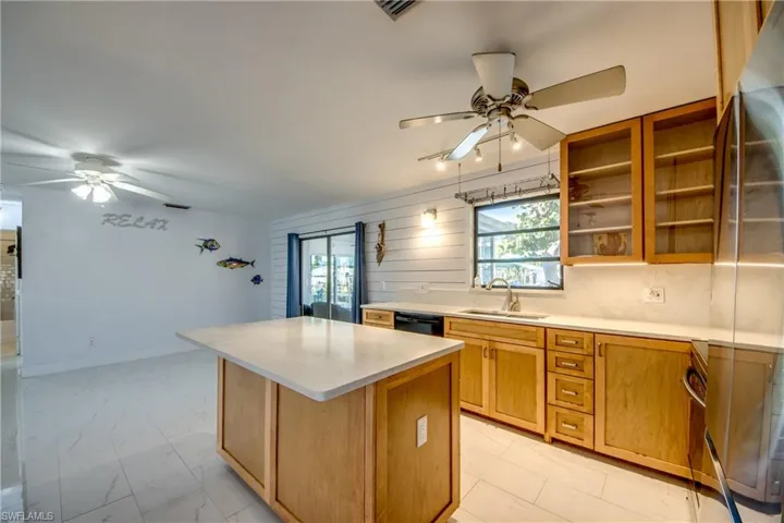 Kitchen with a ceiling fan, brown cabinetry, a kitchen island, and wood walls
