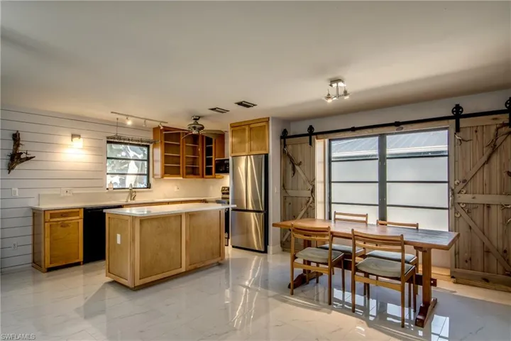 Kitchen featuring a barn door, light marble finish floors, stainless steel appliances, light countertops, and wood walls