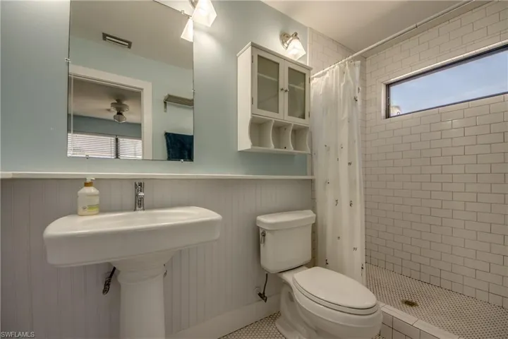 Bathroom featuring a wainscoted wall and a shower stall