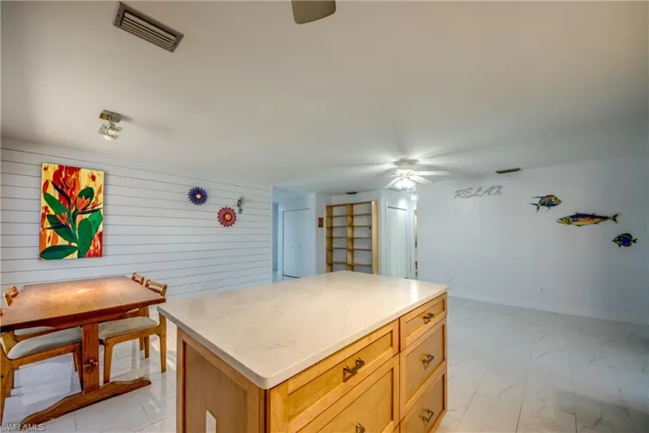 Kitchen with a center island, ceiling fan, light marble finish flooring, and light brown cabinets