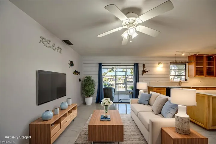 Living area with wood walls, light marble finish floors, and ceiling fan