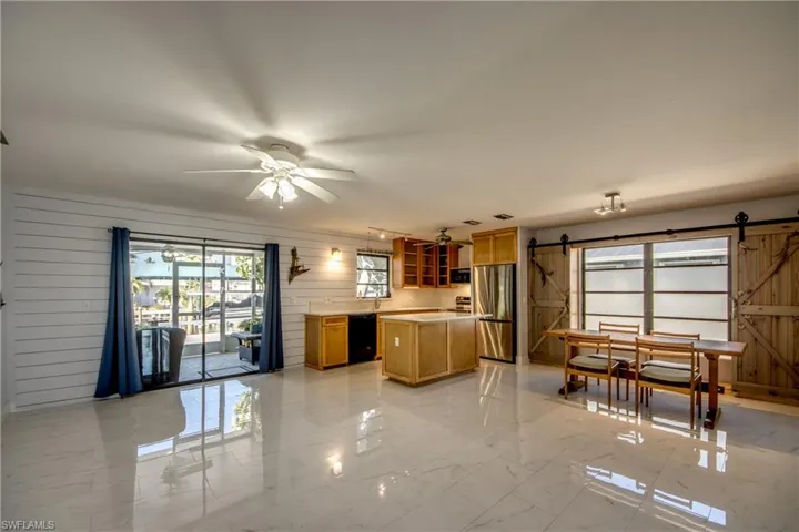 Kitchen with a barn door, wooden walls, light marble finish floors, and a center island