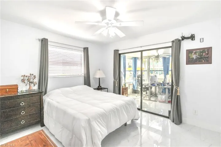 Bedroom featuring light marble finish flooring, access to exterior, and ceiling fan