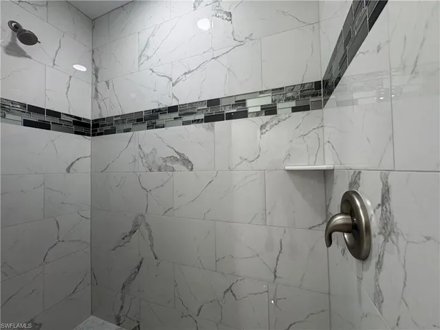 Shower featuring large format white tile with gray veining