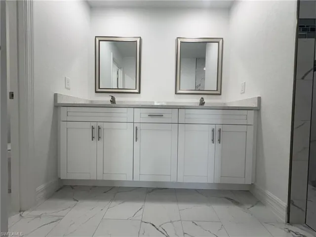 Dual vanity with white shaker-style cabinetry, undermount sinks, and light-toned countertops