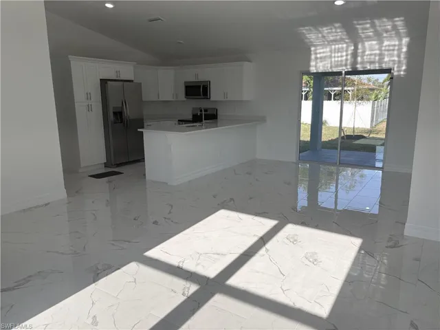 Contemporary kitchen featuring white cabinetry, stainless steel appliances, and a central island with a breakfast bar