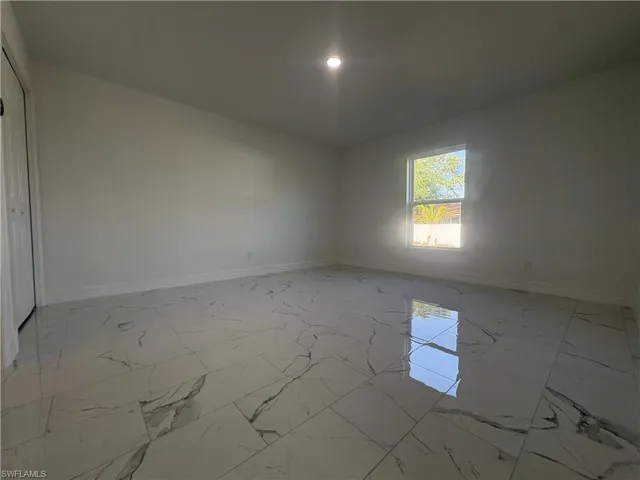 Interior room featuring polished tile flooring, a window providing natural light, white painted walls, and a recessed ceiling light fixture