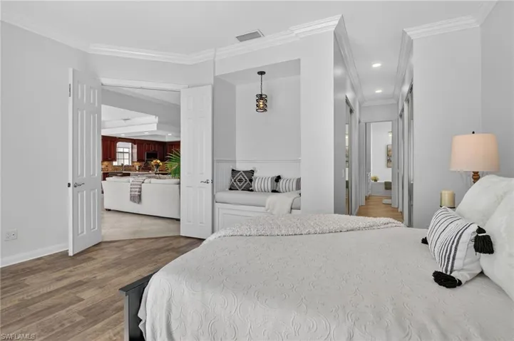 Bedroom with ornamental molding, built in nook, light wood-type flooring, ensuite bathroom, and recessed lighting