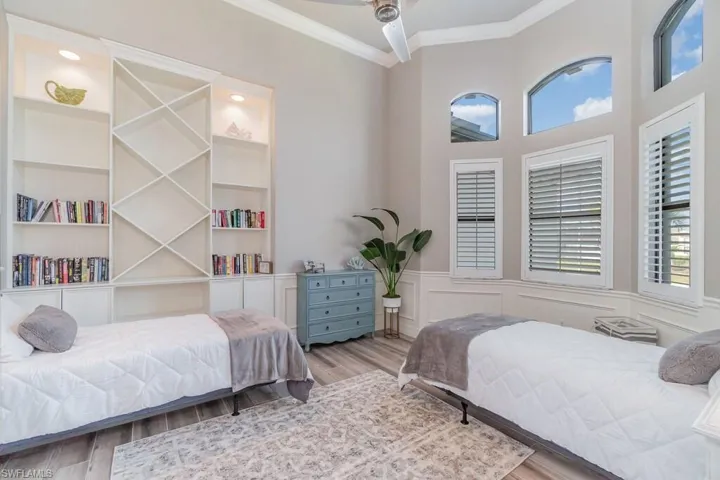 Bedroom with wainscoting, a decorative wall, light wood-type flooring, and crown molding