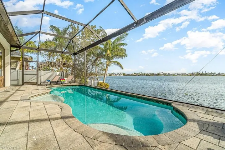Outdoor pool featuring a patio area, glass enclosure, and a water view
