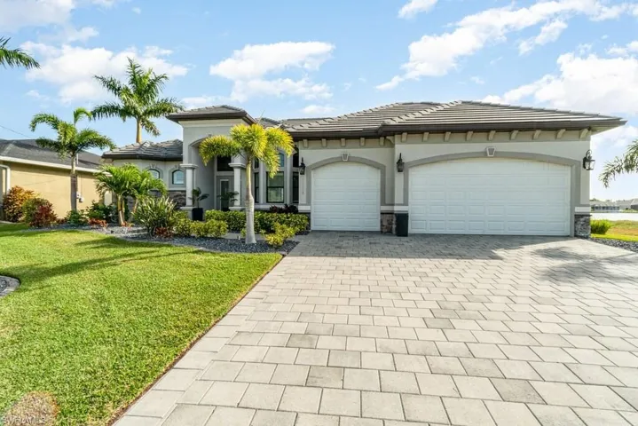 View of front facade with a garage, a tile roof, decorative driveway, stucco siding, and a front yard