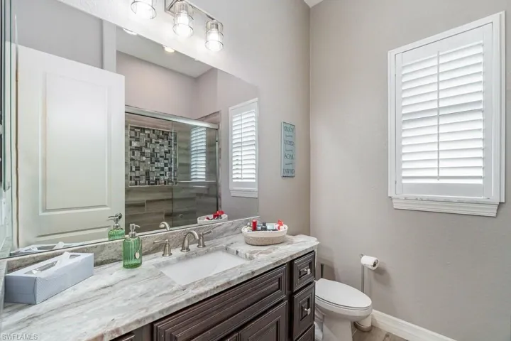 Bathroom with toilet, a shower stall, baseboards, and vanity