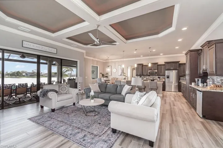 Living room with a water view, ceiling fan, visible vents, and crown molding