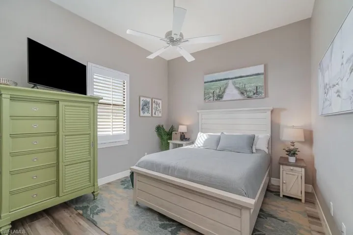 Bedroom with ceiling fan, baseboards, and dark wood-style flooring