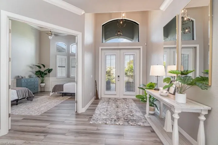 Entrance foyer with ornamental molding, french doors, wood finished floors, and baseboards