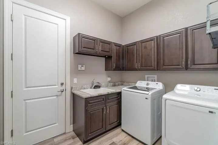 Washroom featuring light wood-style flooring, independent washer and dryer, a sink, and cabinet space