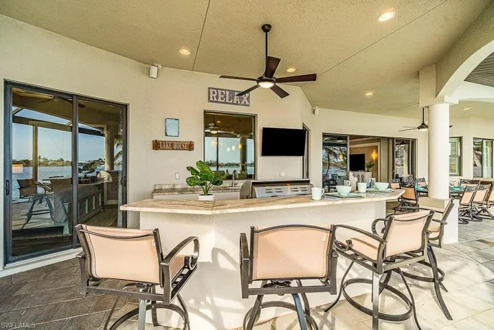View of patio with outdoor wet bar, a water view, and ceiling fan