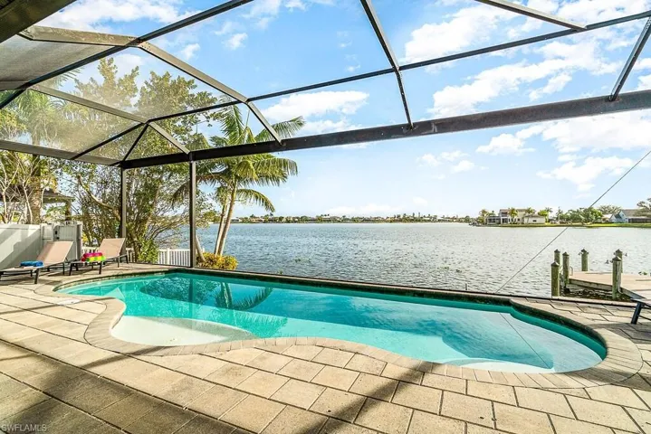 Outdoor pool featuring a patio, a water view, and a lanai