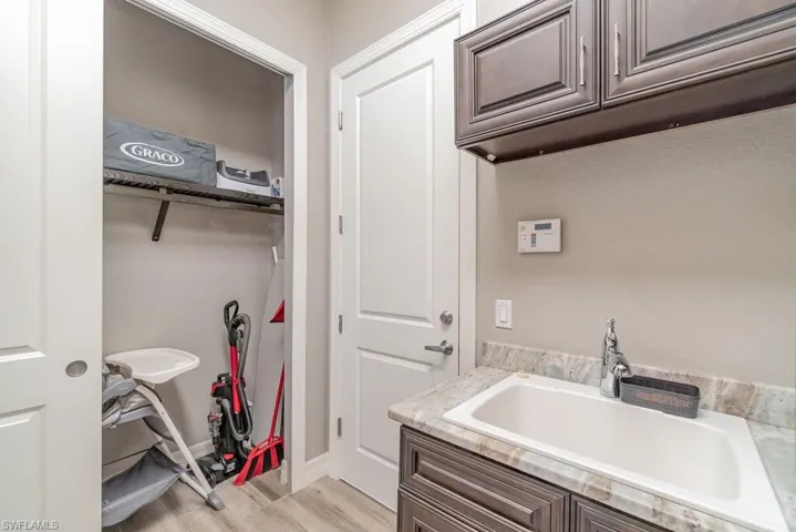 Laundry area with light wood-type flooring, a sink, and baseboards