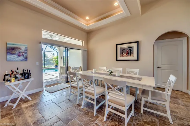 Dining room featuring stone tile floors, baseboards, a high ceiling, crown molding, and a raised ceiling