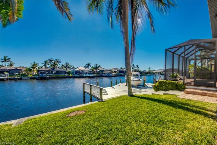 View of dock with a lanai, a residential view, a lawn, and a water view