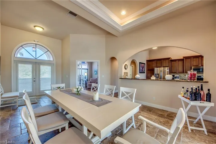 Dining room featuring baseboards, visible vents, stone tile flooring, french doors, and a towering ceiling