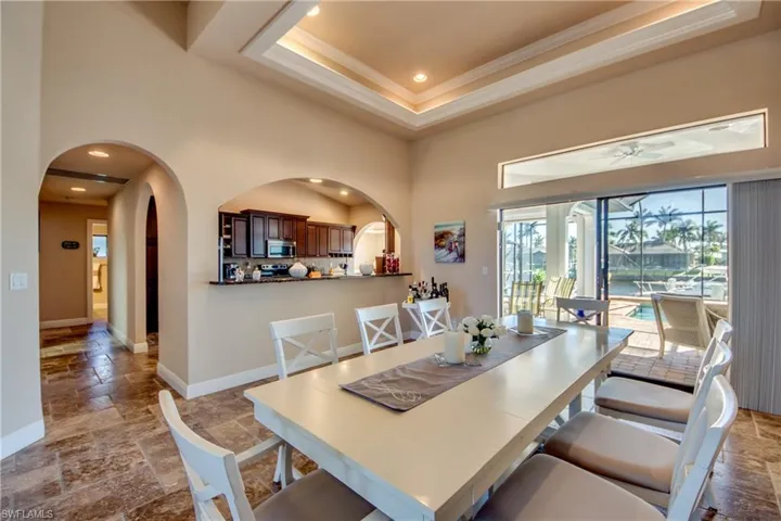 Dining room featuring stone tile floors, a towering ceiling, recessed lighting, baseboards, and ceiling fan