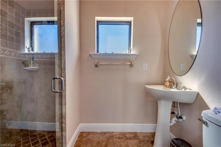 Full bathroom featuring plenty of natural light, a stall shower, toilet, and baseboards