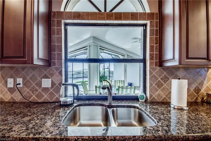 Kitchen featuring dark stone counters, backsplash, and a sink
