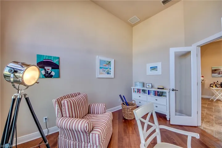 Living area with visible vents, baseboards, wood finished floors, and a towering ceiling